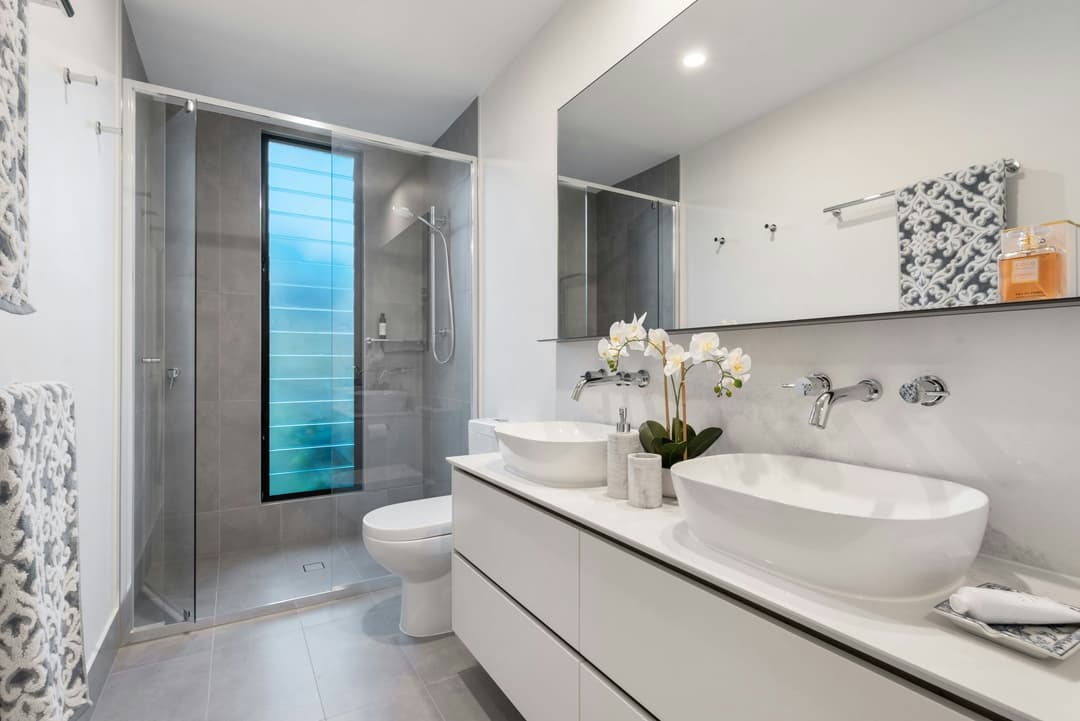 picture of a newly remodeled bathroom with gray stonework and dual luxury sinks and marble countertops