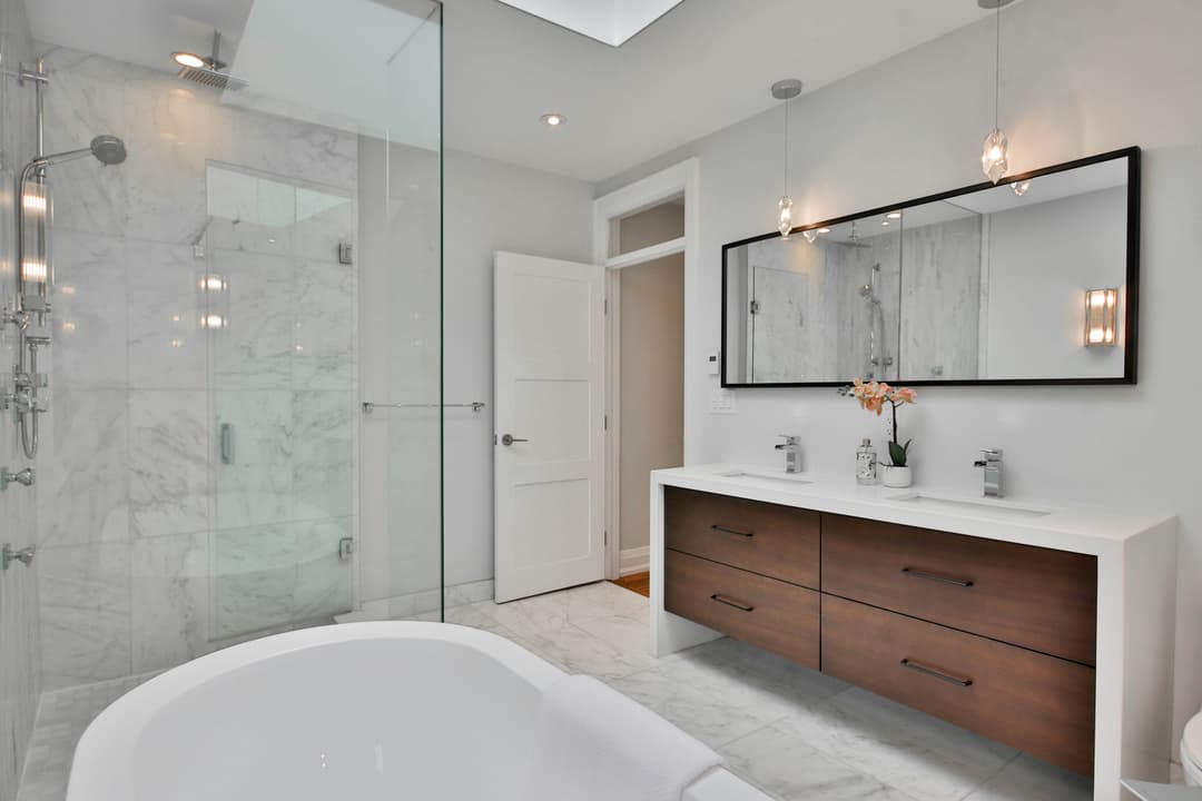picture of a newly remodeled bathroom with a luxury white bathtub and brown luxury drawers